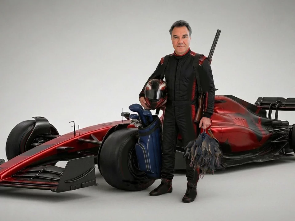 Hunter in a Formula 1 race suit holding a shotgun and red-legged partridges beside a red F1 car and a golf bag